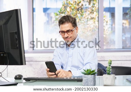 Businessman working in office with computer sitting at desk. Portrait of mature age, middle age, mid adult man in 40s.