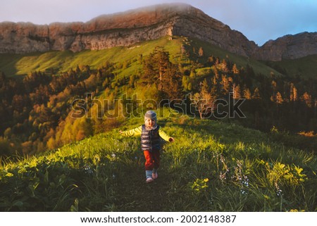 Child running in mountains travel family vacations lifestyle 2 years old toddler smiling hiking outdoor happy emotions nature sustainable tourism Royalty-Free Stock Photo #2002148387
