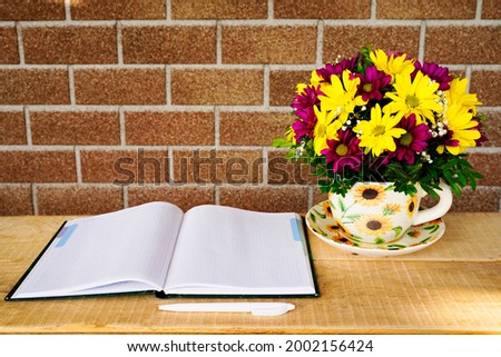 Composition of flowers in a tea mug and a notebook on a wooden table in the morning in summer or spring. Postcard good morning, Happy Mother's Day, March 8th.
