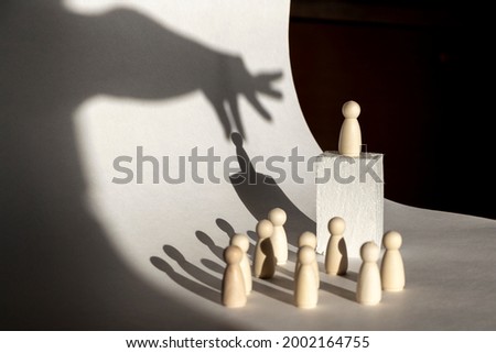 The man on the orator's pedestal is manipulated with a hand from above. Manipulation concept Royalty-Free Stock Photo #2002164755