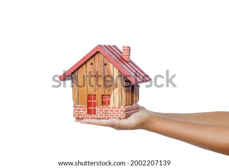 Wooden house model on woman hand isolated on white background.