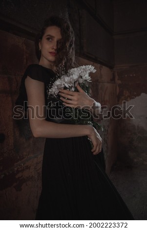 Curly girl in a black dress against the backdrop of the city