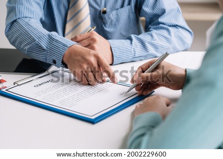 Close-up of estate agent hand pointing to the customer holding pen to sign a contract at the signing. 
