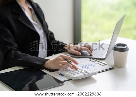 Close-up of businesswoman hand using a calculator with a laptop to calculate at the office.