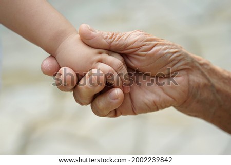 Hands of senior man and little baby close up. Soft focus image.                   Royalty-Free Stock Photo #2002239842