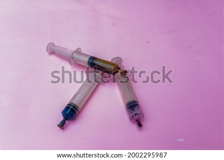 syringe with black ink.  printer ink filling isolated on pink background