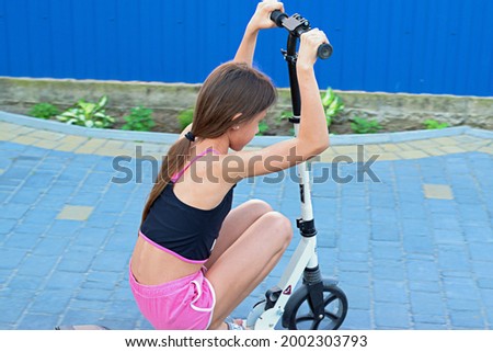 
A girl in the yard rides a scooter