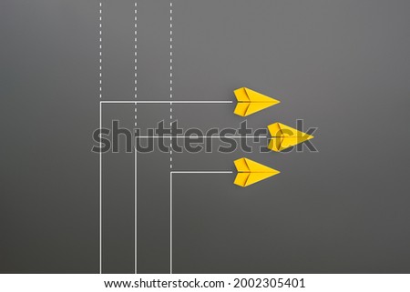 New normal concept with Group of yellow paper planes in new direction on gray background