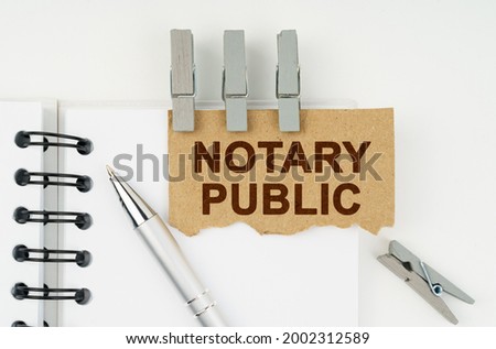 Business and finance concept. On a white background lies a notebook, a pen, clothespins and cardboard with the inscription - Notary Public