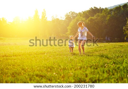 happy family on nature walks in the summer. mother and child run on field