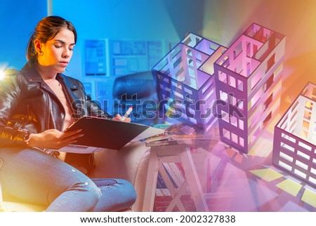 Female architect next to 3d models of buildings. Development of construction projects. Large models of houses without roofs on the table of a construction engineer. Work of a designer in construction.