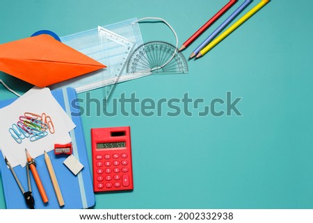 Variety of stationery items with blue face mask, lying on blue background. A copy space for text or words. Back to school or work concept photo.