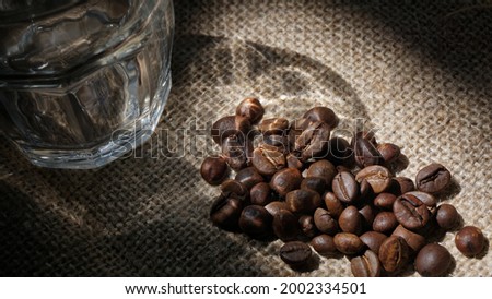 Medium light roasted coffee beans and coffee glass on a hemp background

