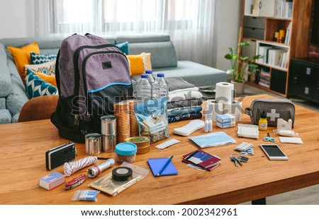 Emergency backpack equipment organized on the table in the living room Royalty-Free Stock Photo #2002342961