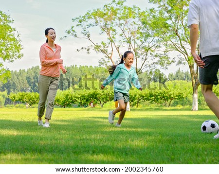 Happy family of three playing football in the park high quality photo