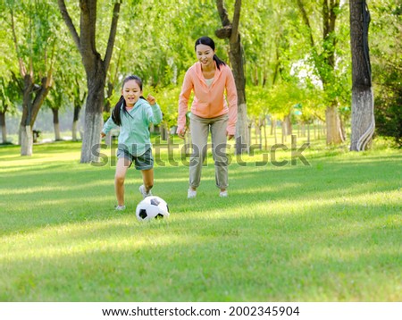 Happy mother and daughter are playing football in the park high quality photo