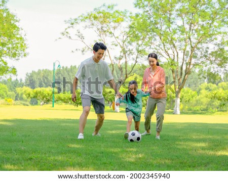 Happy family of three playing football in the park high quality photo