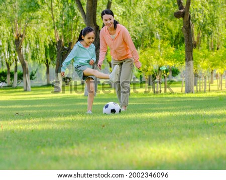 Happy mother and daughter are playing football in the park high quality photo