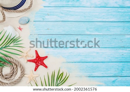 The concept of a holiday at the sea. Shells, a straw hat and sand on a turquoise wooden photo background. A picture for summer holidays with space for text. Top view.