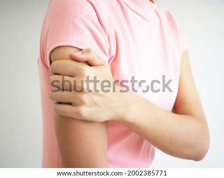 Woman having arm pain on a white background. closeup photo, blurred.