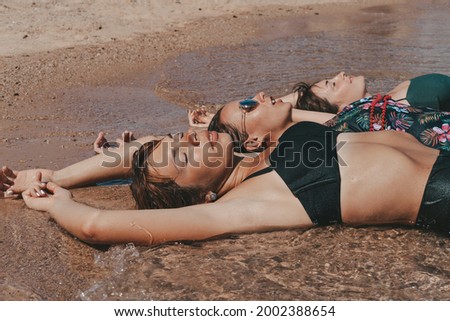 Group of beautiful young women have a rest on a beach. Friends walking on the beach and laughing on a summer day