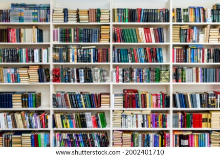 Library with bookcases. Many different books on the shelves. Large selection of books in a bookcase. Blur background. Royalty-Free Stock Photo #2002401710