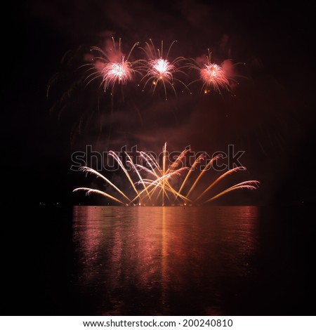 Colorful fireworks with reflection on lake and night sky in background.