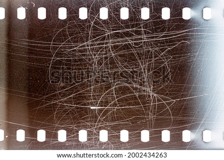 Dusty and grungy 35mm film texture or surface. Perforated camera film isolated on white background.
