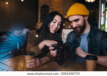 Cheerful male and female amateurs editing pictures on slr camera during education private lesson for improve photo skills, prosperous Caucasian friends recalls to pleasant moments with pictures