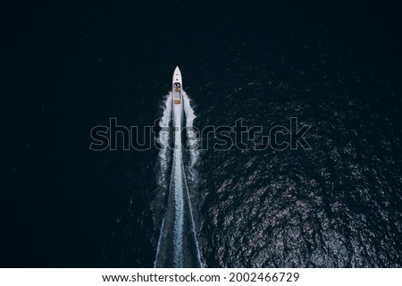 Speedboat movement on the water.Speedboat wave speed water. Large white boat driving on dark water. Speedboat on dark blue water aerial view. Speed boat faster movement top view. Royalty-Free Stock Photo #2002466729