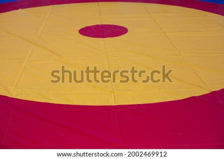 A sports ground for wrestling. Soft flooring for sport. Ring for judo and karate. The background is from the red circle in yellow. Soft coverage for workouts and tournaments.