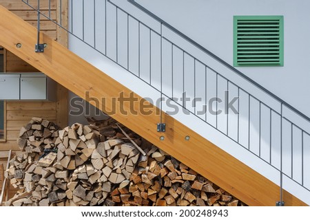 Stacked firewood, stairway and air vent of residential house