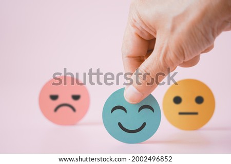 hand choose green paper cut, happy smiling face on pink background for mental health assessment ,positive thinking, world mental health day ,customer review, experience, satisfaction survey concept Royalty-Free Stock Photo #2002496852