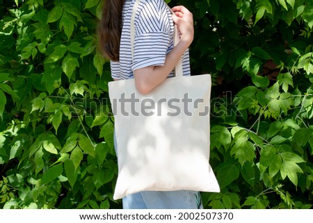 Empty reusable canvas tote bag mockup. Natural canvas eco-friendly shopper bag on girl's shoulder. Mockup for presentation of design or brand Royalty-Free Stock Photo #2002507370