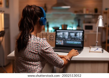 Woman working with video footage on laptop using modern software. Content creator in home working on montage of film using modern software for editing late at night.