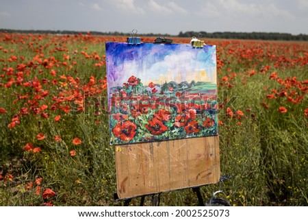 Painting depicting poppies on an easel against the background of a poppy field.