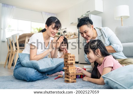 Asian family spending time together on holiday in living room at home. Attractive happy parents, father and mother play wood block toy with young two kid girl daughter in house. Activity relationship. Royalty-Free Stock Photo #2002527059