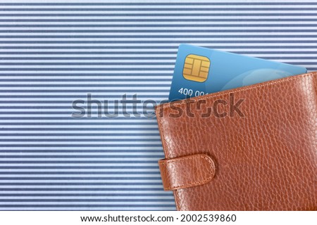 A credit card in a stylish modern wallet on blue background.