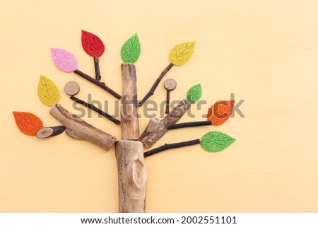Image of wooden growing tree on pastel yellow background