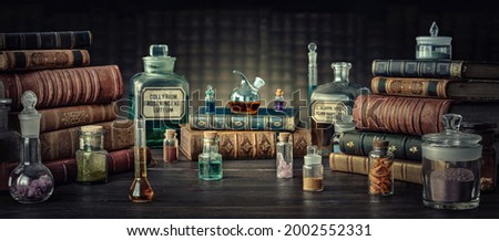Glass bottles, old books on table of a scientist. Medicine, chemistry, pharmacy, apothecary, alchemy history background. Translation from labels-eyewash astringent, morphine hydrochloride and almonds. Royalty-Free Stock Photo #2002552331