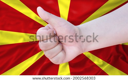 Hand makes a thumbs up sign on the background of the flag of Macedonia. like, good, positive