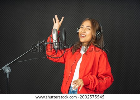 Asian singer woman in a recording studio using a studio microphone with passion in music recording studio