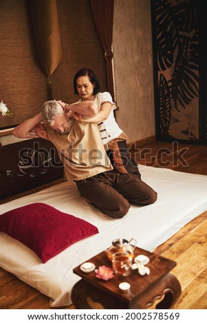 Asian woman treating seniour patient with gymnastics