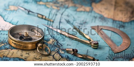 An old geographic map with navigational tools: compass, divider, ruler, protractor. View of the workplace of ship's captain. Travel, geography, navigation, tourism and exploration concept background.