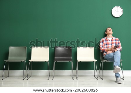 Man with smartphone waiting for job interview indoors