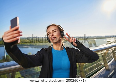 Smiling sportswoman taking selfie after training outdoors