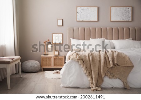 Cozy bed with soft linens in light room Royalty-Free Stock Photo #2002611491