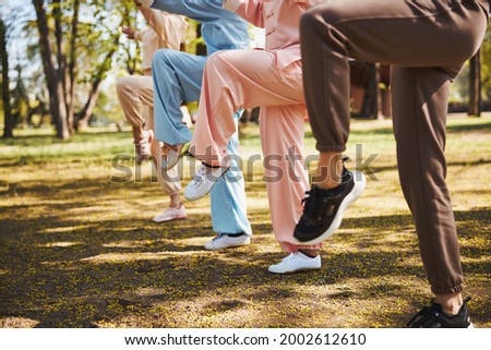 Raised legs of four people, doing exercise in park Royalty-Free Stock Photo #2002612610