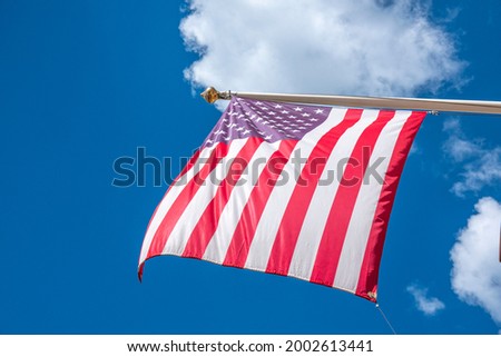 Flag of United States of America waving in blue sky. Low view to american USA flag