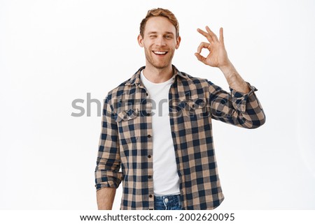 Alright, well done. Smiling man with red hair, showing OK okay sign and nod in approval, being supportive, say yes, give positive good feedback, agree with you, standing over white background
